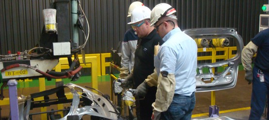 Three people working on a car chassis