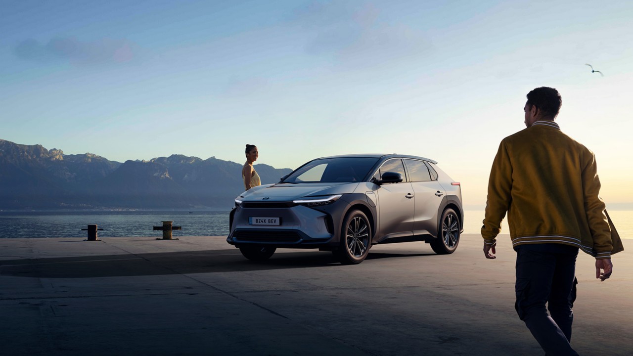 Two people standing next to a battery electric car